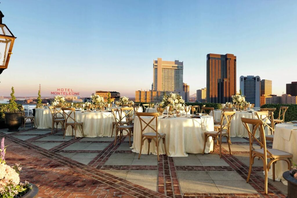 Rooftop wedding reception setup at the Ritz-Carlton New Orleans with city skyline views and elegant white florals.