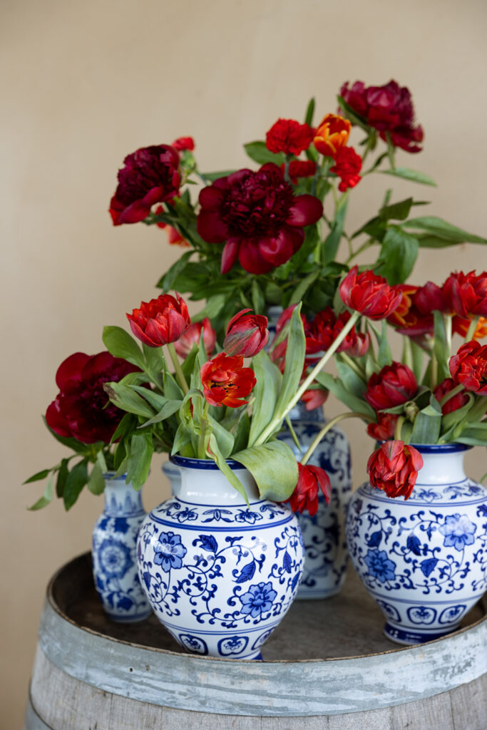 Editorial floral design featuring red tulips and peonies in blue and white vases — a Fox & Quinn example of contrast and balance in wedding design and planning.