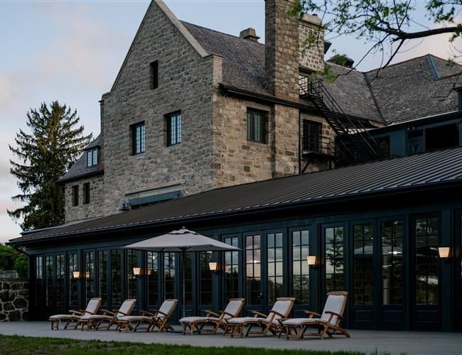 The Ranch Hudson Valley, an editorial Upstate New York wedding venue with stone architecture, black-framed windows, and outdoor terrace seating.