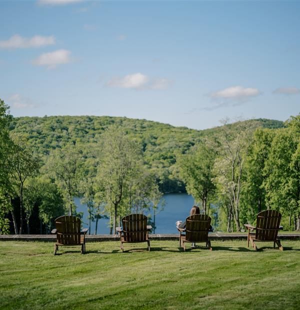 Lakeside view at The Ranch Hudson Valley, one of the most scenic Upstate New York wedding venues, featuring Adirondack chairs and forested hills.