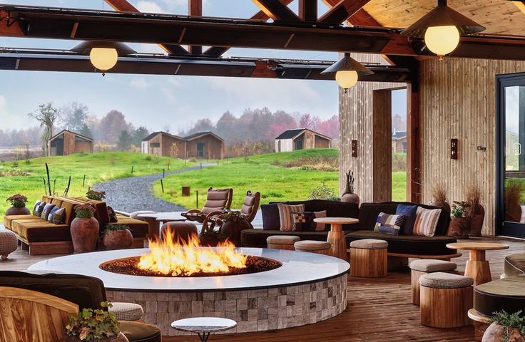Wildflower Farms, a luxury Upstate New York wedding venue in the Hudson Valley, featuring an open-air lounge with modern firepit and views of hillside cabins.