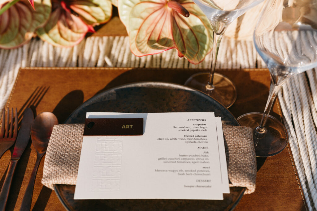 Reception menu card with coral anthurium and a leather tag at Son Vell, Menorca