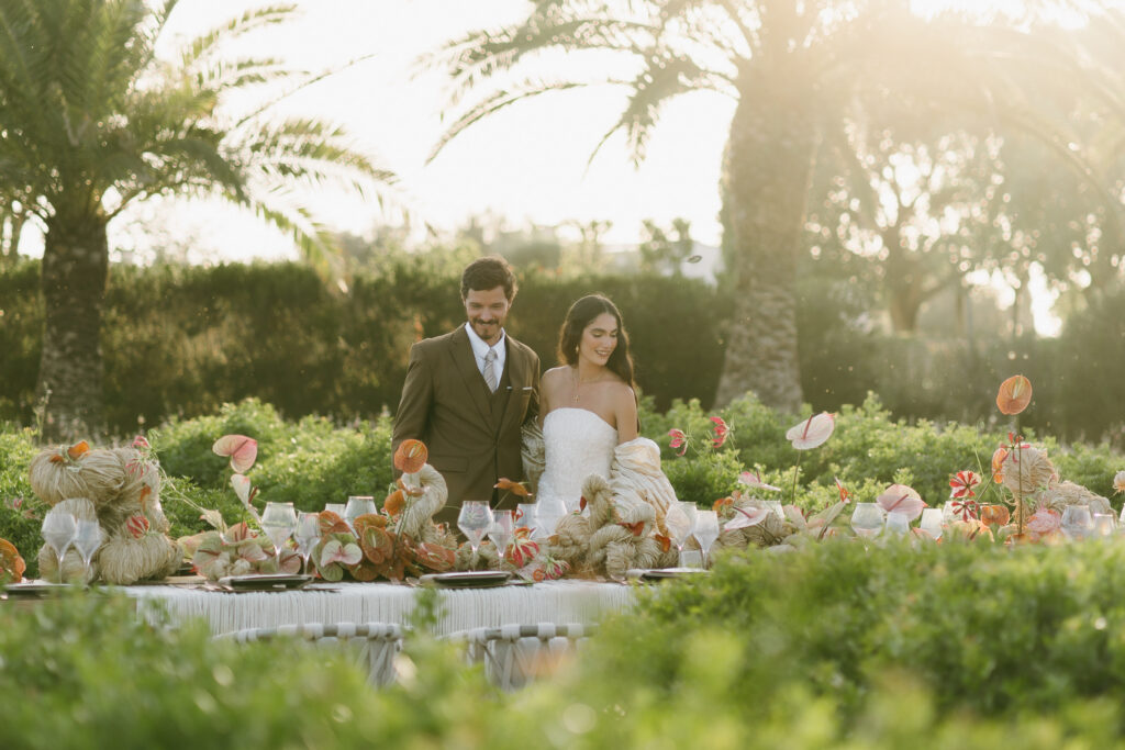 Bride and groom at a floral reception table among the garden hedges at golden hour, Son Vell, Menorca