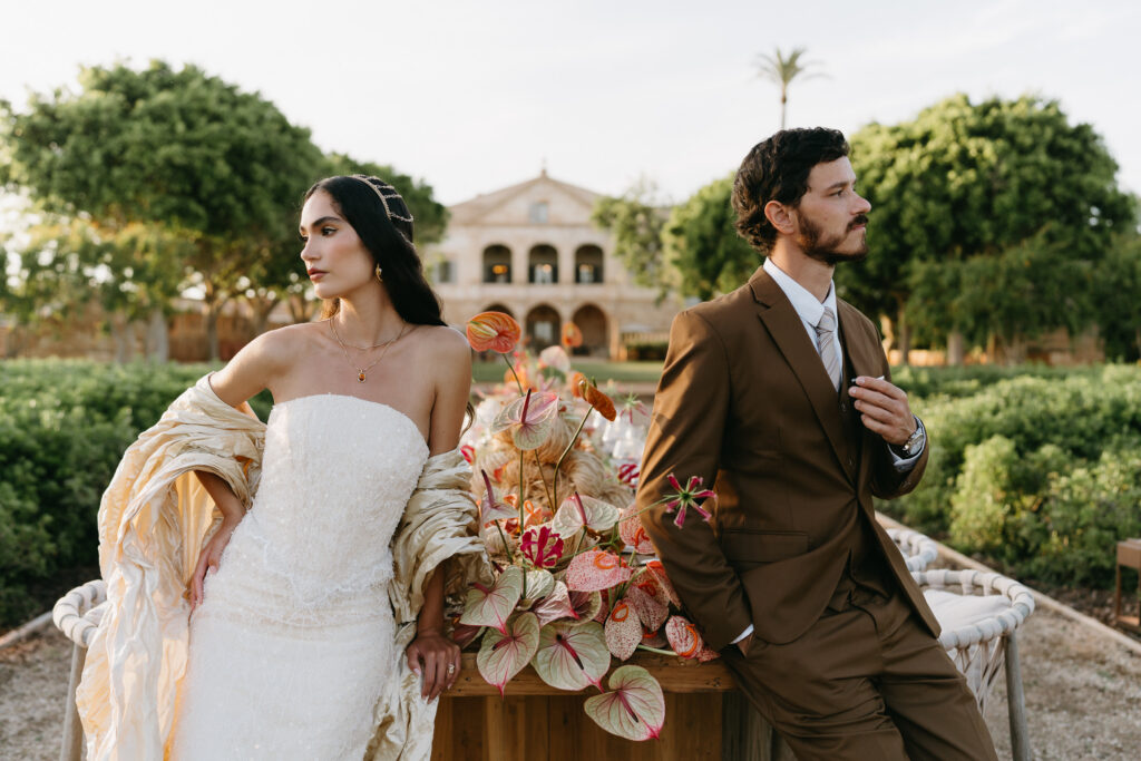 Bride and groom beside a floral reception table with the Son Vell manor behind, Menorca