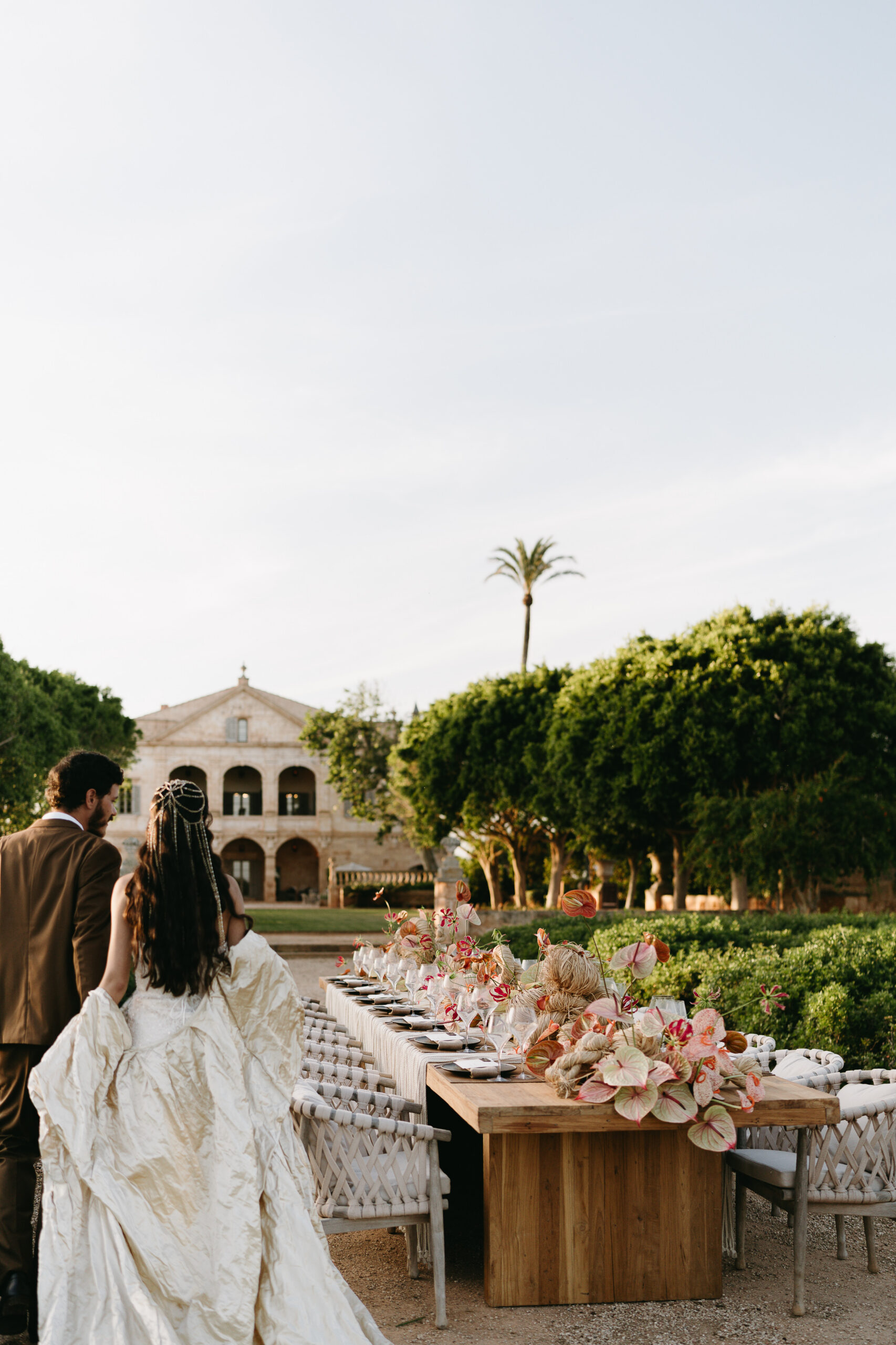 Outdoor wedding reception table with coral anthurium and sculptural grasses below the manor loggia at Vestige Son Vell, Menorca
