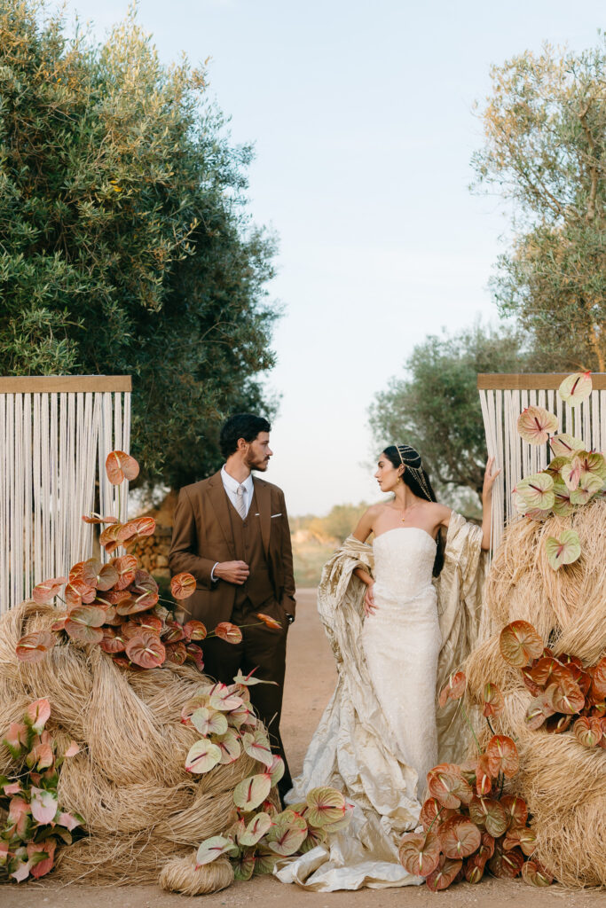Bride and groom between rope panels and raffia floral installations in the olive grove at Son Vell, Menorca