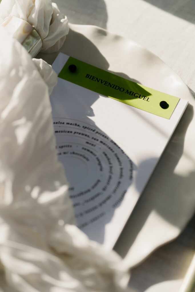 Place setting with a spiral menu and a green leather welcome tag
