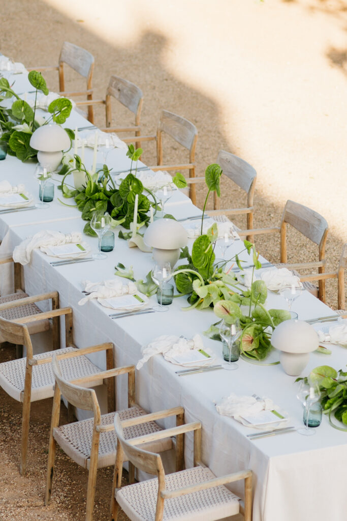 Overhead view of a white welcome dinner table with green anthurium and globe lamps