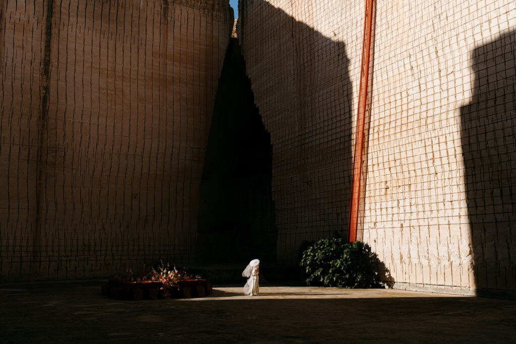 Bride and groom standing in the dramatic shadowed cleft of Lithica Quarry, Menorca, beneath towering sunlit limestone — destination wedding designed and produced by Fox & Quinn.