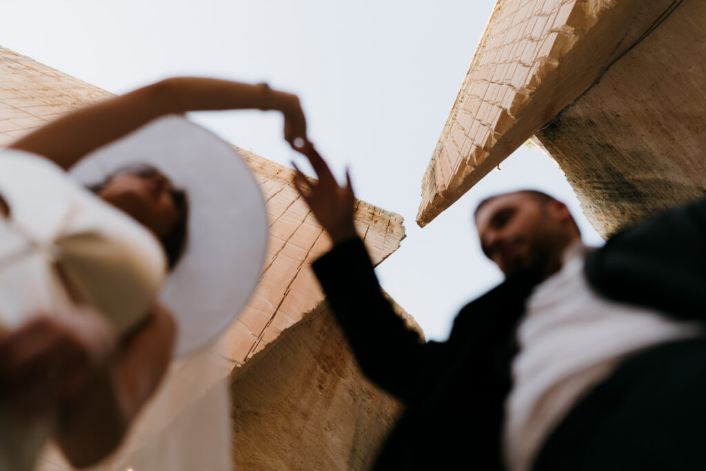 Bride and groom in close silhouette against the carved limestone walls and sky of Lithica Quarry, Menorca.