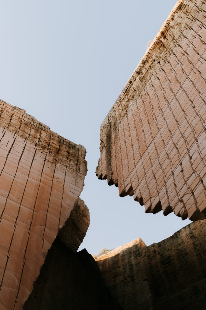 Towering carved limestone walls of Lithica Quarry meeting at a dramatic cleft against the sky, Menorca.