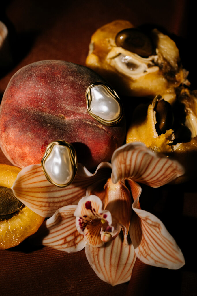 Pearl and gold bridal earrings styled with peaches and a cymbidium orchid, Lithica Quarry wedding details, Menorca