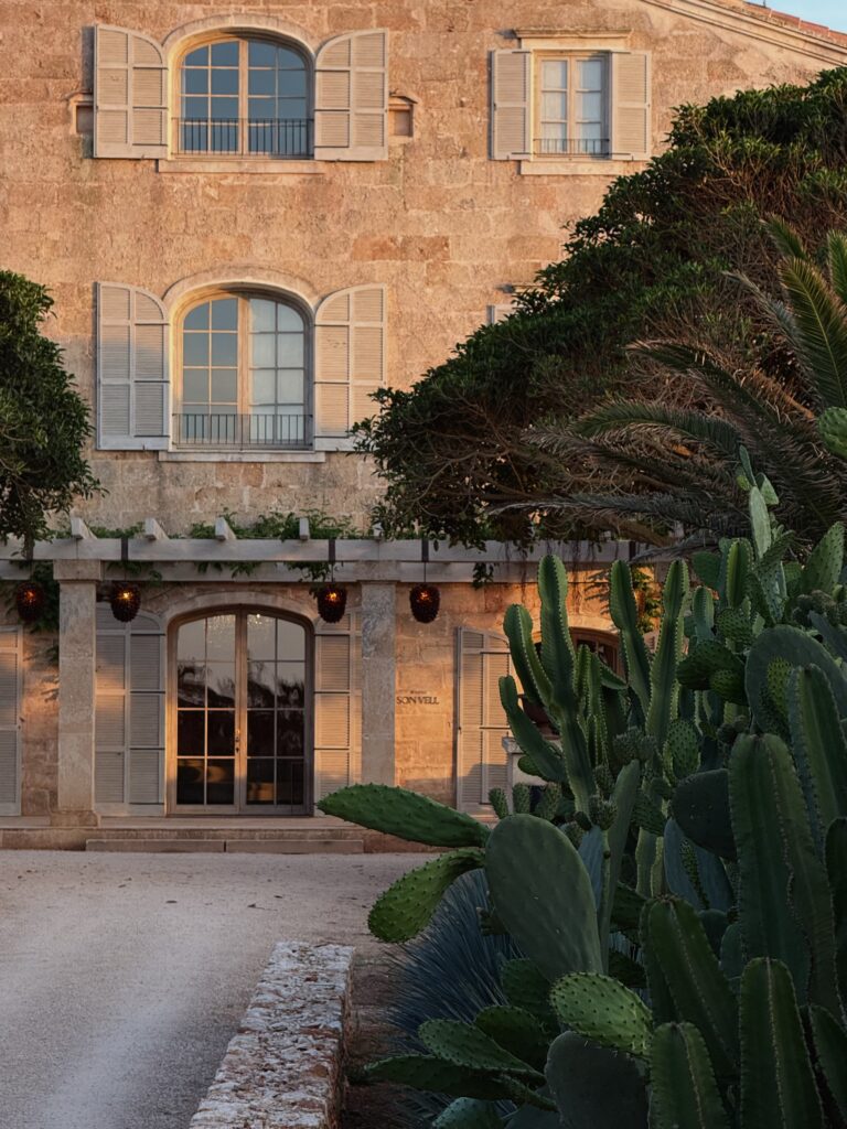 Arched stone entrance of the Vestige Son Vell manor with shuttered windows and cactus gardens, Menorca
