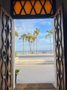 Tropical ocean view framed by carved wooden doors at a boutique seaside hotel in La Paz, Mexico.