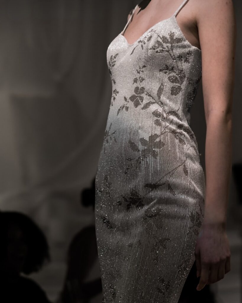 Close-up of a glittering ivory gown with tonal floral embroidery and spaghetti straps from EnAURA Bridal’s Spring 2026 collection