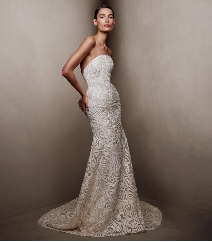 Model wearing the Greta gown by Naeem Khan, a strapless embroidered column dress with train and sculptural lace patterning.