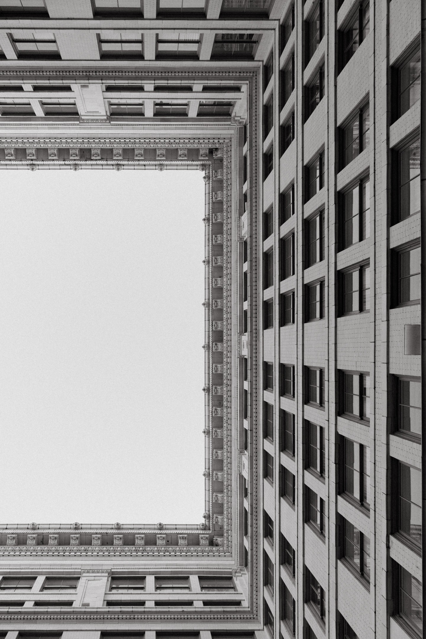 Black and white photo looking up through the central courtyard of the Ritz-Carlton New Orleans. Framed by symmetrical historic architecture, the image draws the eye upward to the top floor, where the private residence suite is located.