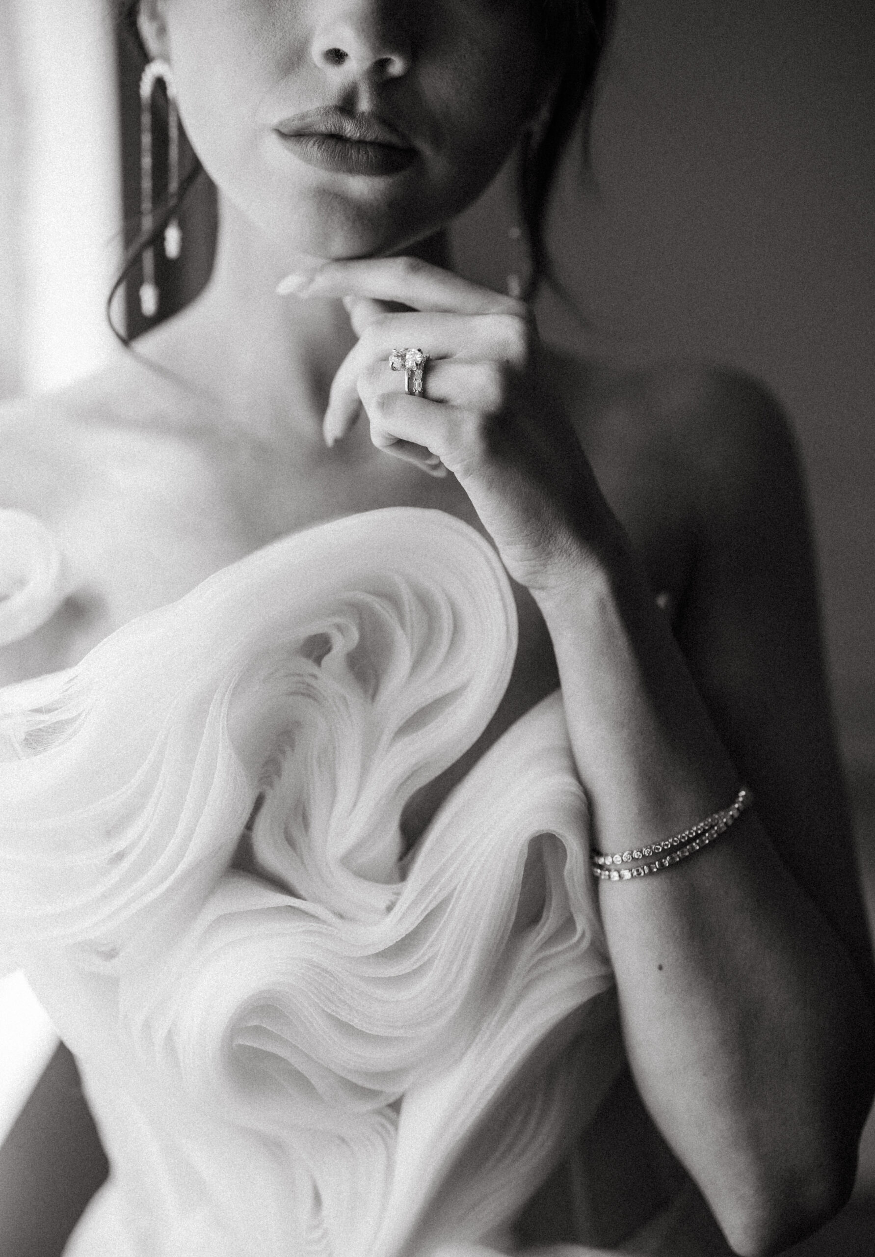 Close-up of a bride in a sculptural tulle gown, showcasing her engagement ring and diamond bracelet
