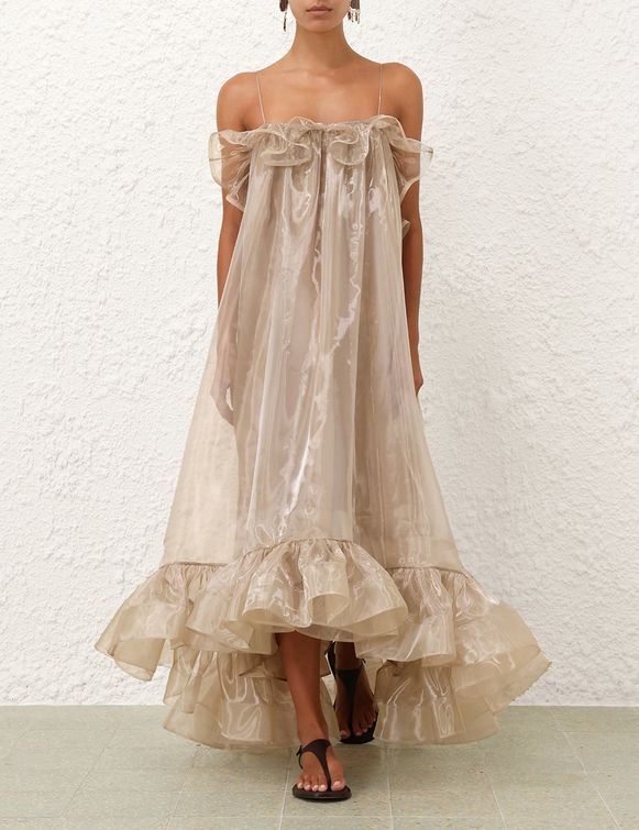 Champagne-hued organza dress with a ruffled high-low hem and delicate straps, evoking ethereal movement and whimsical charm.